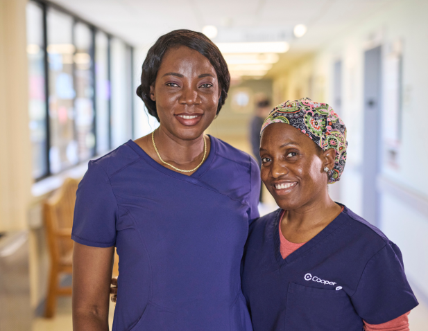Two smiling nurses in blue scrubs.