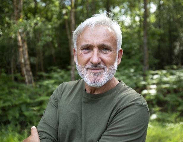 Older man with beard wearing a green shirt outdoors.