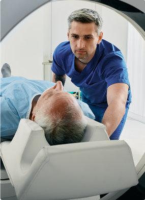 Medical technician guiding a patient into a CT scanner for imaging.