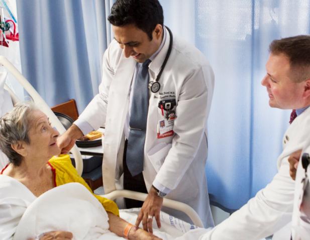 An elderly patient talking with doctors while receiving care.