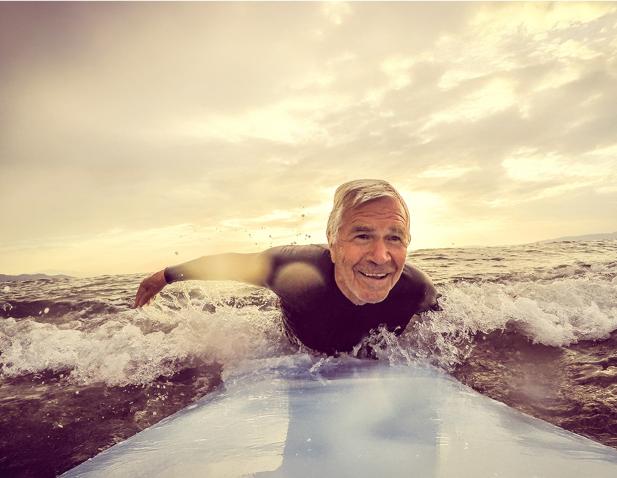 An older man happily surfing.