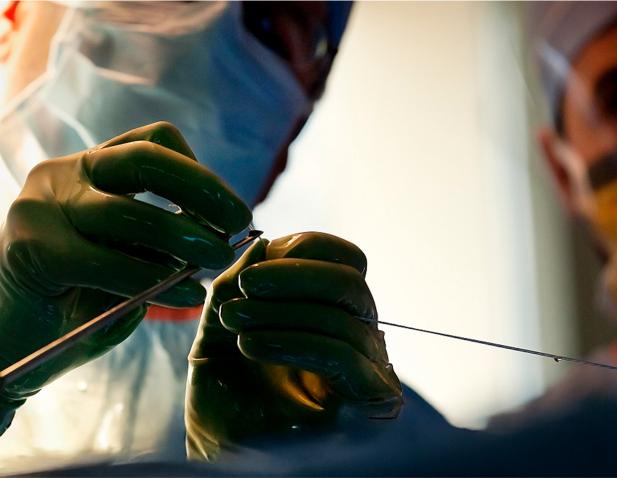 Close-up of a surgeon’s gloved hands inserting an arthroscopic instrument during a minimally invasive procedure.