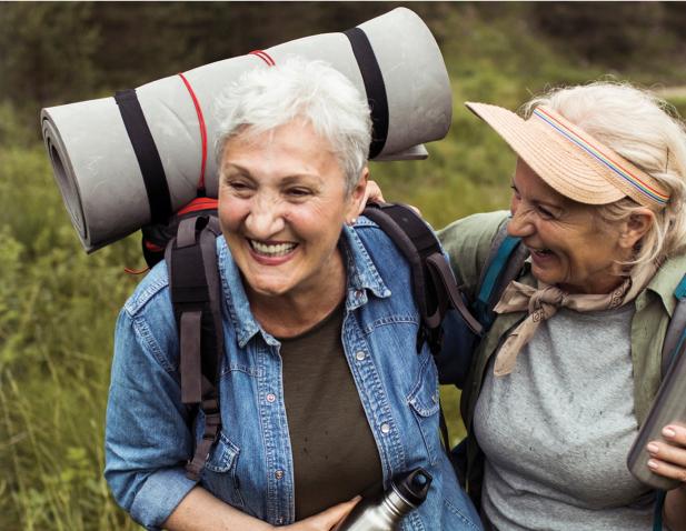 Two older woman with outdoor gear, happily hiking together.
