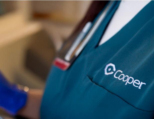 Close-up of a Cooper University Health Care provider’s scrub top and name badge.