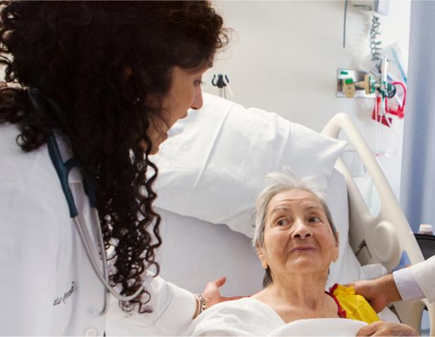 Doctors talking and taking care of a patient in a hospital room.