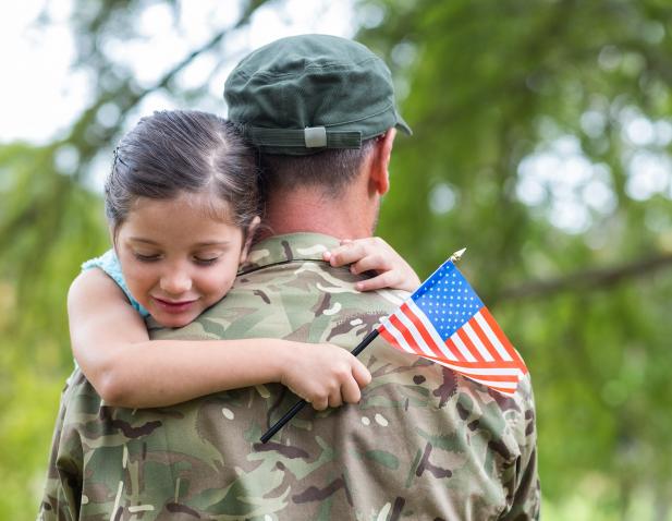 2025_military_veteran_child_hugging_father_holding_flag_iStock-488521228_1538x956.jpg