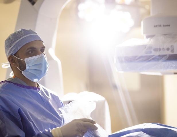 Masked doctor with surgery light over patient