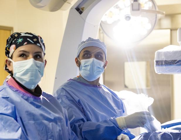 Surgeon and tech performing surgery with surgical light in background