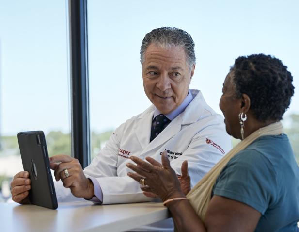 Doctor with iPad talking to female patient window in the background