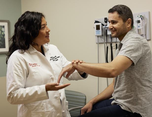 Dr. Woozley performs wrist exam on male patient