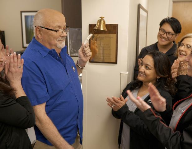 Photo of patient Wayne ringing the bell to celebrate the end of his cancer treatment.