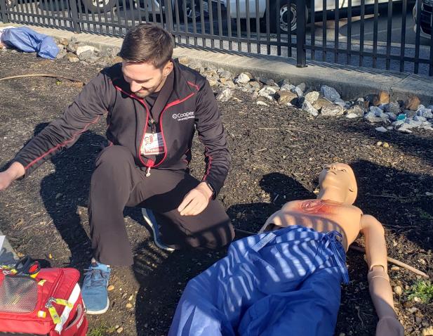EMT in attends to a simulated patient on street in urban setting during a field training exercise