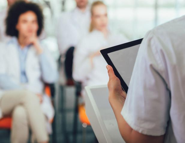 medical personnel in white coats sit in a classroom facing a lecturer