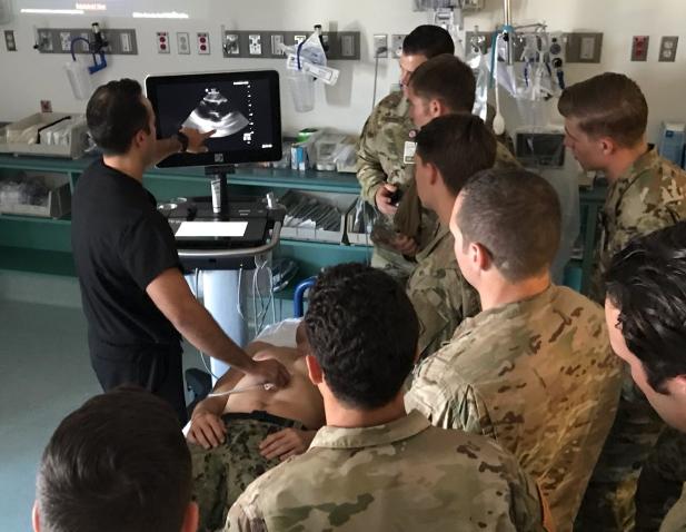 Dr. Simon Sarkisian demonstrates emergency ultrasound for a room full of military trainees wearing fatigues