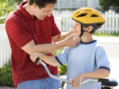 Father fixing kids helmet.