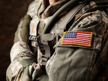 photo of person in military garb shown from neck to waist with arms crossed
