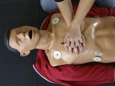 Person performs chest compressions on CPR dummy