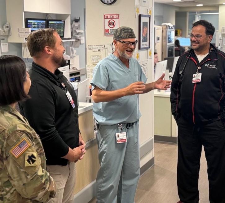 Cooper trauma surgeon, Co-CEO, and military personnel pause during an emergency department tour