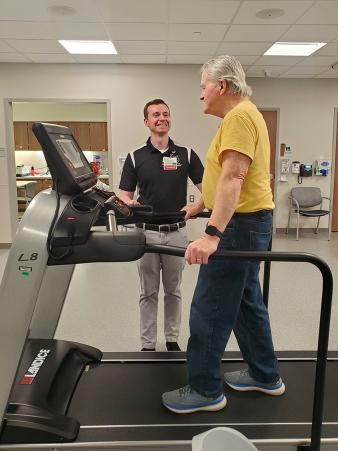 Male patient walks on treadmill as physical therapist encourages him at Cooper Moorestown Campus